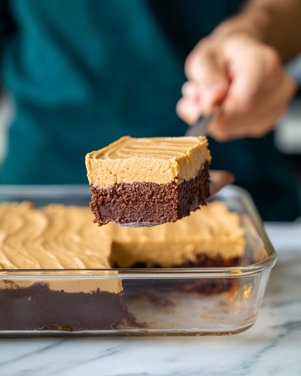 The image shows five square pieces of a two-layer dessert on a white marbled surface. Each piece has a thick, dark brown bottom layer with a moist texture and some small light spots, topped by a slightly thick, smooth golden brown layer with a creamy texture that spreads evenly but with some soft ridges on top. The pieces are arranged unevenly, with the focus on the front left piece showing more detail in the layers. The background is softly blurred with a light blue tone. Photo taken with an iphone --ar 4:5 --v 7