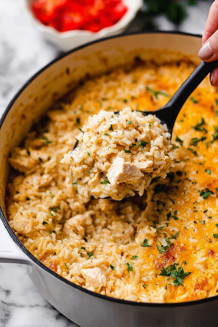 One Pot Queso Chicken and Rice, cheesy chicken and rice skillet, easy cheesy chicken dinner, Tex-Mex one pot meal, quick creamy chicken rice - This image shows a close-up of a white pot filled with a creamy, cheesy rice dish. The dish has one main layer of cooked rice mixed with small pieces of chicken and sprinkled with chopped green herbs. The rice looks soft and slightly orange-yellow from the cheese sauce that covers it evenly, with some melted cheese visible on top near the edges. A black spoon lifted by a woman's hand holds a scoop of the rice mixture in the center of the pot. The background shows a blurred white bowl with chopped red tomatoes. The whole scene is set on a white marbled surface. photo taken with an iphone --ar 2:3 --v 7