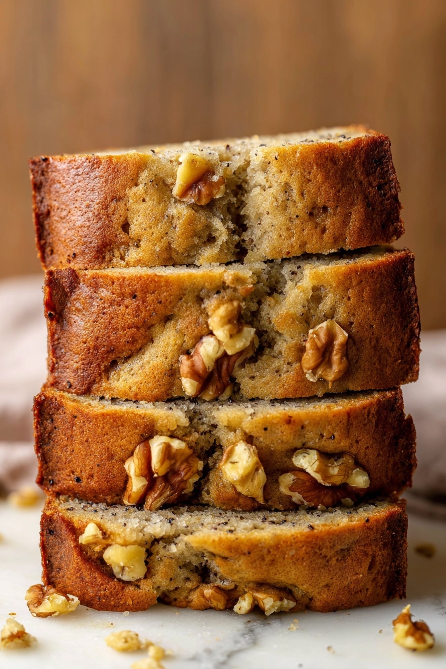 Best Vegan Banana Bread, vegan banana bread, egg-free banana bread, healthy banana bread, plant-based banana bread - A stack of four thick banana bread slices sits on a white marbled surface, each slice showing a soft, moist interior with a light brown color and speckles of dark spots from bananas. The crust is golden brown and slightly crumbly with several walnut pieces embedded both on the top and inside the bread. Some walnuts are well visible on the top edges, adding texture. The bread has a homemade rustic look with a few cracks and uneven parts along the sides and top. The background is a warm wooden texture blurred out softly. Photo taken with an iphone --ar 2:3 --v 7