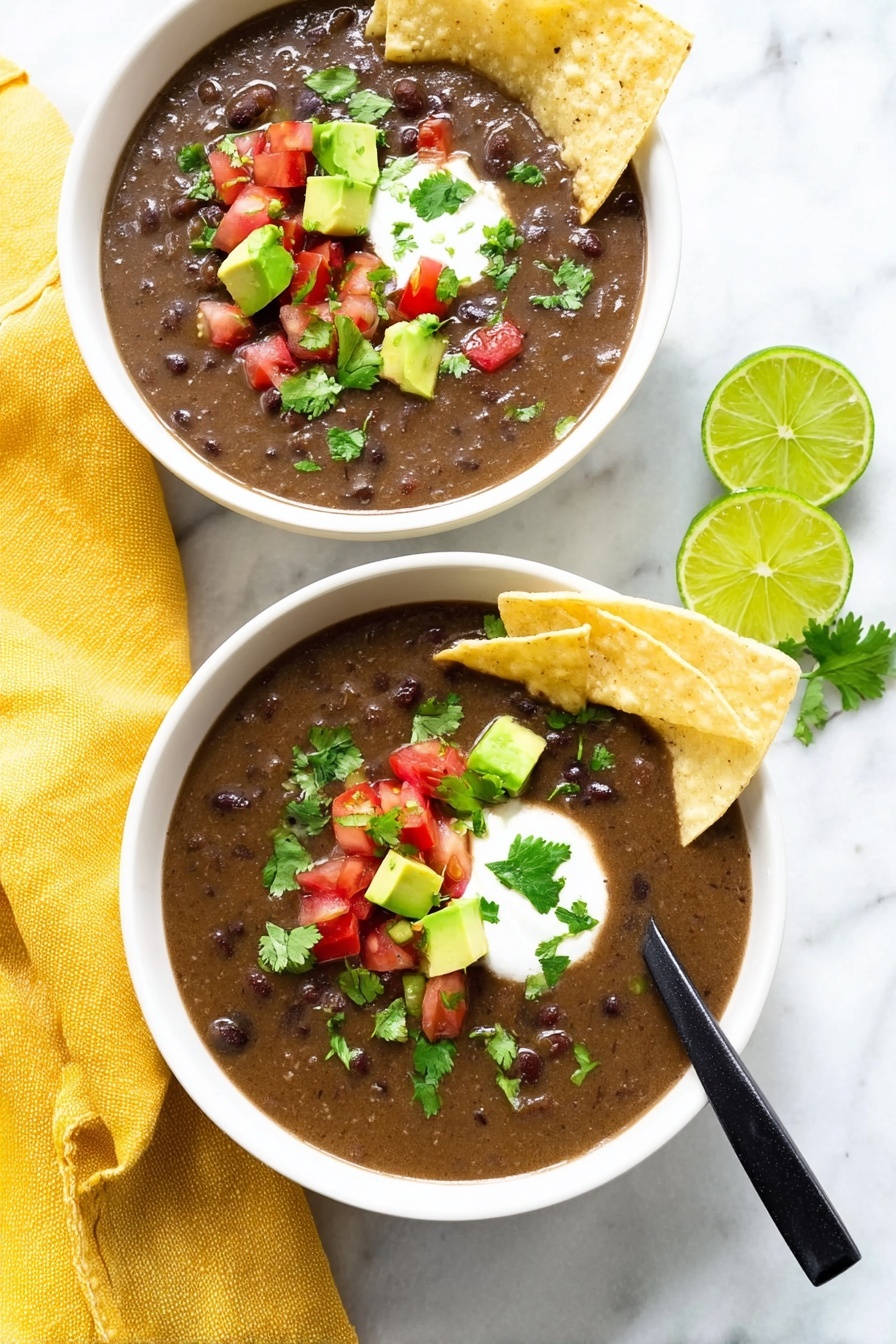 Vegan Black Bean Soup, vegan black bean soup recipe, healthy black bean soup, hearty vegan soup, easy vegan black bean dish - The image shows two white bowls filled with dark brown bean soup that has a thick texture. Each bowl has two light beige tortilla chips placed on the side, slightly dipped into the soup. On top of the soup, there are small cubes of bright green avocado, small pieces of red tomato, chopped green cilantro, and a dollop of white cream in the center. One bowl has a black spoon resting inside. The bowls sit on a white marbled surface with a yellow cloth napkin next to one bowl and two lime wedges nearby. The scene is bright and clean. Photo taken with an iphone --ar 2:3 --v 7
