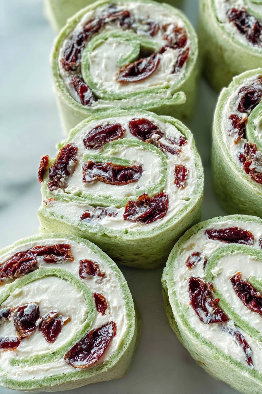 Cranberry Feta Pinwheels, Cranberry Feta Wraps, Easy Holiday Appetizer, No-Bake Cranberry Pinwheels, Festive Cheese Appetizer - The image shows several spiral pinwheel wraps arranged closely on a white marbled surface. Each wrap has three visible layers: the outer layer is a light green soft flatbread, the middle layer is a thick white creamy filling, and the innermost layer consists of dark red dried fruit pieces evenly spread throughout. The wraps are sliced to show the spiral pattern clearly, with the green flatbread curling around the white filling and red fruit in a tight spiral. The texture of the flatbread looks soft and slightly porous, while the filling is smooth and creamy. Photo taken with an iphone --ar 2:3 --v 7