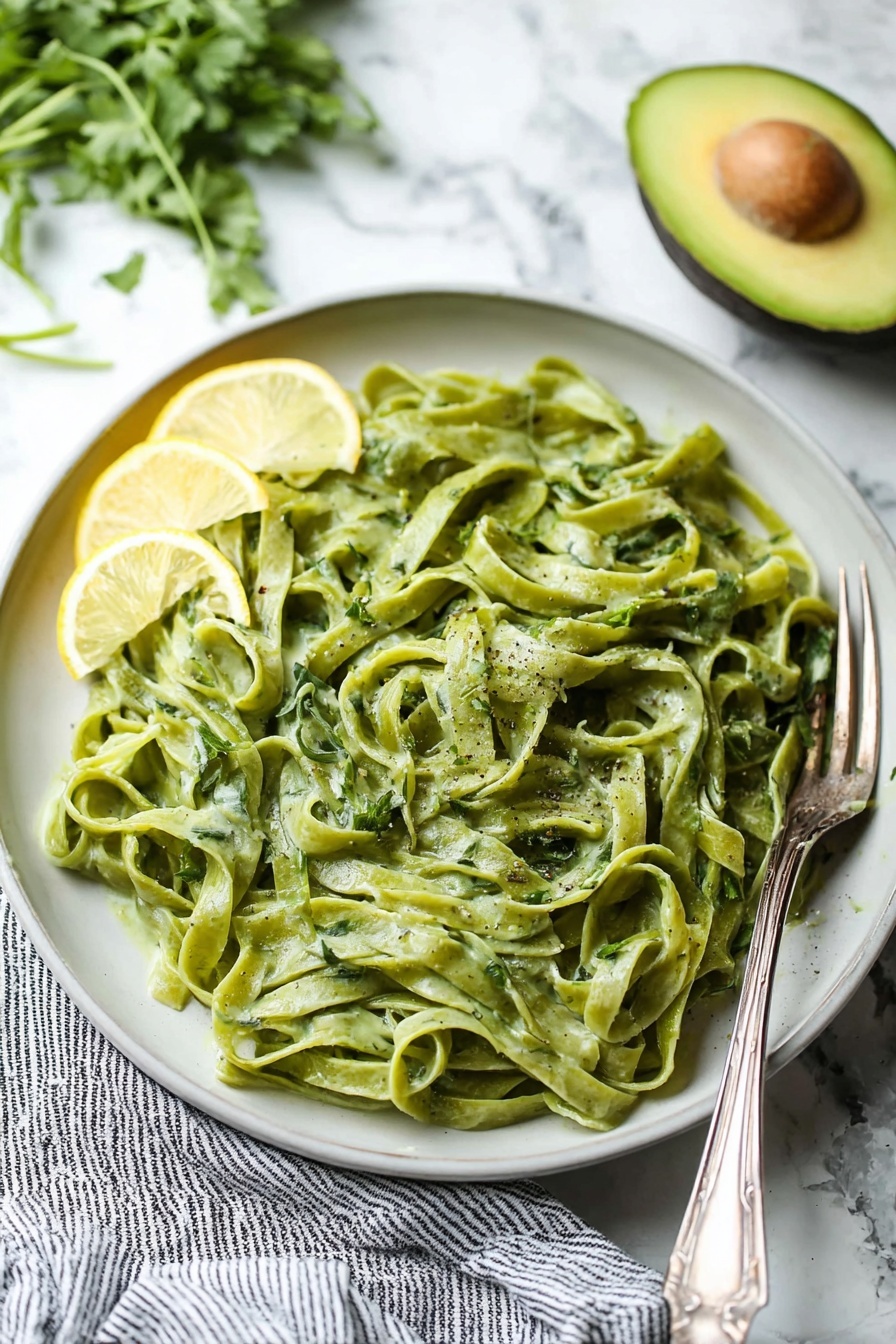 Avocado Lemon Pesto, healthy avocado pesto, creamy lemon pesto sauce, vegan pesto ideas, versatile pesto dishes - A clear blender jar with four sharp blades at the bottom contains a thick, smooth mixture of bright green color with a slight creamy texture. The blender base beneath is black with a large round silver knob in the center. The jar handle is transparent with a blue tint, positioned to the right, and the whole scene is set on a white marbled surface. photo taken with an iphone --ar 2:3 --v 7