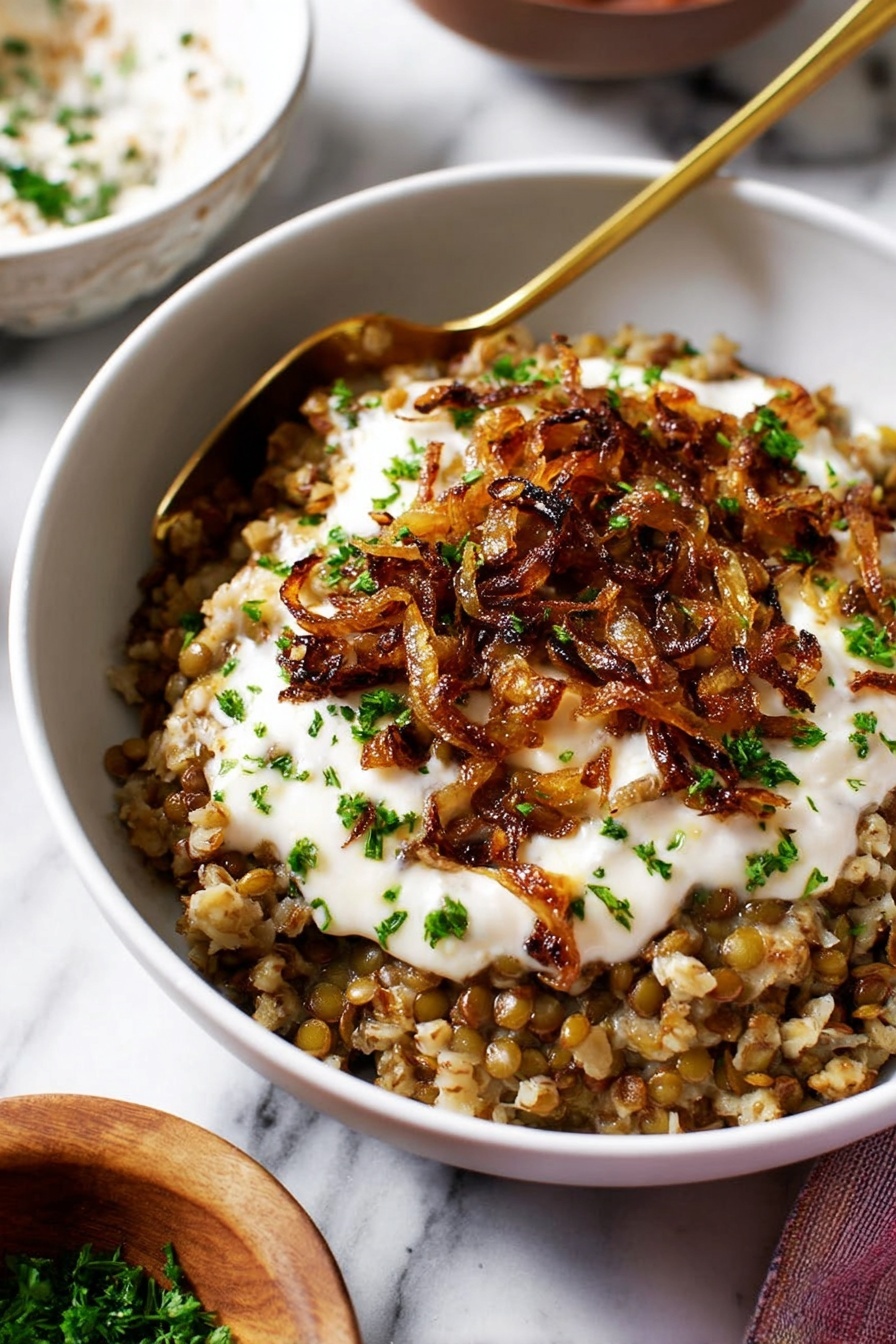 Easy Lentil and Rice Mujadara, Middle Eastern Lentil Dish, Healthy Lentil and Rice Meal, Simple Vegetarian Dinner, Comfort Food Recipes - A white bowl filled with three distinct layers: the bottom layer is a mix of cooked lentils and bulgur, showing a textured, brownish-green color; the middle layer is a thick, creamy white sauce spread unevenly on top; and the top layer consists of caramelized golden-brown onions scattered with small chopped green herbs. There is a gold spoon resting inside the bowl partly covered by the layers. The bowl sits on a white marbled surface with blurred background elements including a white bowl with a brown rim and a small wooden bowl with green herbs. Photo taken with an iphone --ar 2:3 --v 7