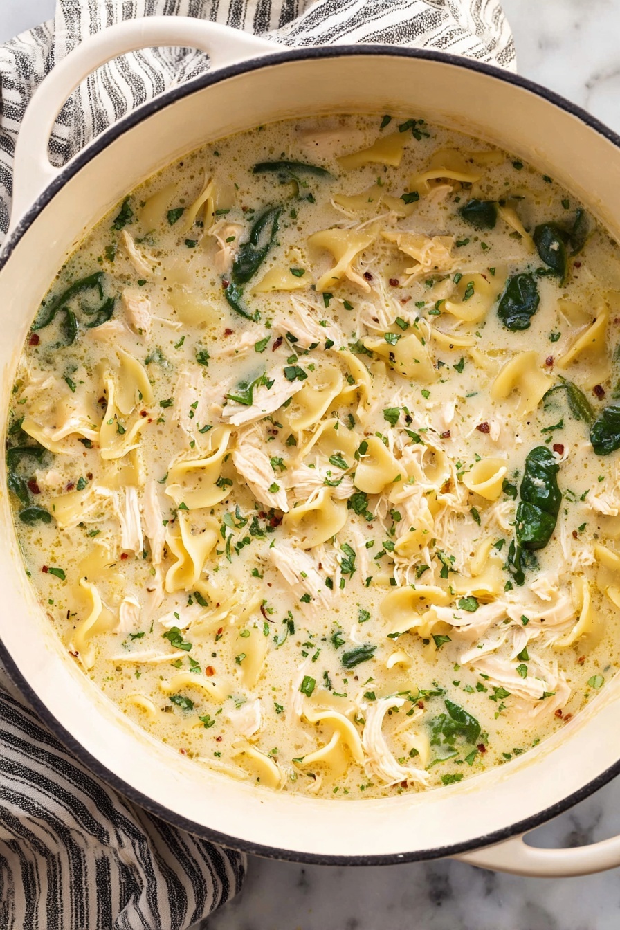 White Lasagna Soup, creamy white lasagna soup, Italian lasagna soup, easy lasagna soup, comforting soup recipes - A white pot filled with creamy soup that has three main layers: shredded white chicken pieces spread evenly, dark green spinach leaves scattered throughout, and curly, pale yellow pasta floating in a thick, light cream broth with small herbs sprinkled all over. The pot is placed on a white marbled surface with a striped cloth under one side. Photo taken with an iphone --ar 2:3 --v 7