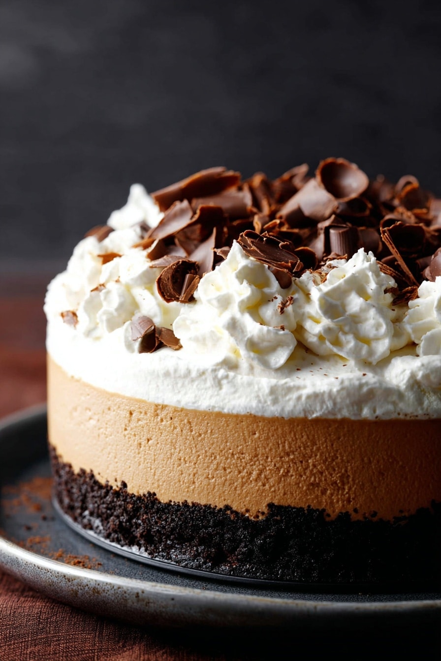 Chocolate Pumpkin Cheesecake with Bourbon Whipped Cream, pumpkin cheesecake dessert, fall pumpkin cheesecake, bourbon whipped cream recipe, chocolate pumpkin pie - A three-layer dessert is shown, starting with a dark crumbly chocolate base at the bottom, followed by a thick smooth light brown creamy layer in the middle, topped with a generous fluffy white whipped cream layer. The whipped cream is decorated with scattered dark brown curled chocolate pieces. The dessert sits on a dark surface with a soft dark background. photo taken with an iphone --ar 2:3 --v 7