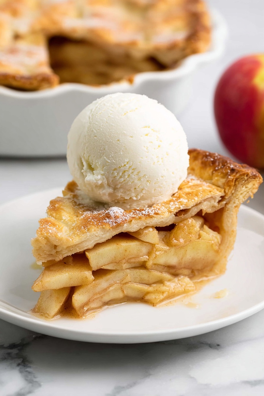 Perfect Vegan Apple Pie, vegan apple pie recipe, plant-based apple pie, homemade vegan dessert, dairy-free apple pie - A slice of apple pie sits on a white plate with a white marbled background. The pie has two layers of golden-brown crust, one on the bottom and one on top, with the top crust slightly cracked and sprinkled with sugar. Between the crust layers are thin slices of light yellow apples mixed with a brown cinnamon spice, visible in the thick filling. On top of the pie slice is a smooth, round scoop of white vanilla ice cream that starts to melt slightly around the edges. In the background, part of the full apple pie in a white dish and a red apple are faintly seen. Photo taken with an iphone --ar 2:3 --v 7