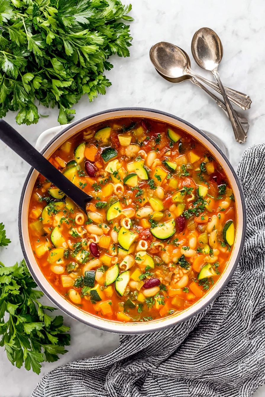 Easy Minestrone Soup, hearty vegetable soup, quick healthy soup, budget-friendly soup recipe, comforting vegetarian soup - A close-up of a white pot filled with colorful minestrone soup, showing about five layers of ingredients in a light red broth. The soup contains small pasta shells, dark red kidney beans, orange carrot cubes, yellow and green zucchini slices, green celery pieces, and diced tomatoes. A ladle is lifting a scoop of soup with a mix of these ingredients, showcasing their textures and colors. The background has a white marbled texture with some green herb leaves visible around the pot. Photo taken with an iphone --ar 2:3 --v 7