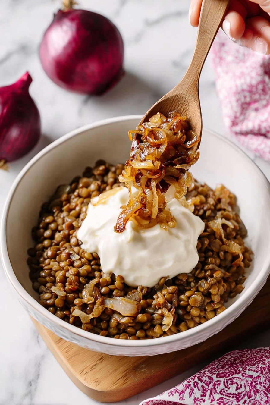 Easy Lentil and Rice Mujadara, Middle Eastern Lentil Dish, Healthy Lentil and Rice Meal, Simple Vegetarian Dinner, Comfort Food Recipes - A white bowl filled with a base layer of cooked lentils mixed with small pieces of caramelized onion, creating a brown and slightly textured bed. On top, there is a smooth, thick white dollop of sauce centered in the bowl. A wooden spoon is positioned above the bowl, held by a woman's hand, scooping some golden-brown caramelized onions over the sauce. The background features a white marbled surface with two whole red onions partially visible in the upper right corner and a softly blurred pink patterned cloth in the lower right. photo taken with an iphone --ar 2:3 --v 7