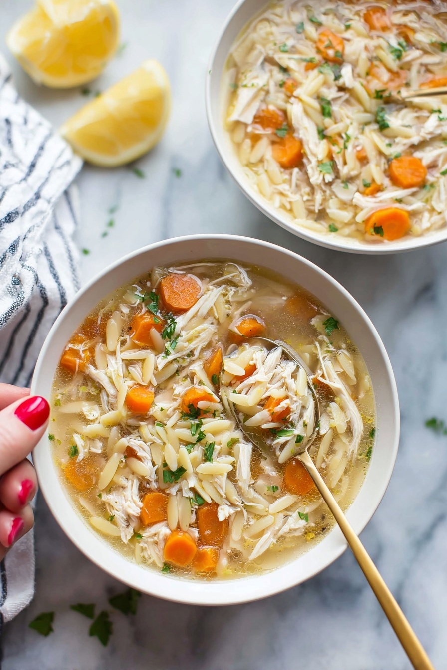Lemon Chicken Soup, Lemon Chicken Soup recipe, healthy lemon chicken soup, easy lemon chicken soup, comforting lemon chicken soup - Two white bowls filled with soup sit on a white marbled surface, each bowl holding a mix of shredded light brown chicken, small round orange carrot slices, and pale yellow orzo pasta floating in a light broth. Bright green herbs are sprinkled throughout the soup, adding fresh color. A gold spoon is held by a woman's hand with red painted nails, lifting a spoonful of soup from the bowl in the front, showing a clear view of the ingredients. In the background, a lemon half and a white-and-blue striped cloth are softly out of focus. photo taken with an iphone --ar 2:3 --v 7