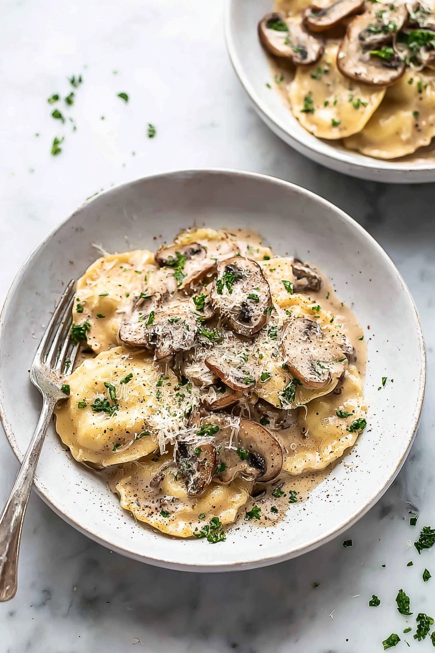 Creamy Mushroom Ravioli, Mushroom Ravioli, Creamy Ravioli, Homemade Mushroom Ravioli, Easy Mushroom Ravioli - The image shows a white bowl filled with two layers of round ravioli pasta covered in a creamy light brown mushroom sauce with visible slices of brown mushrooms on top and scattered parsley leaves for garnish. The sauce coats the pasta fully, giving a smooth, glossy texture, and there is a sprinkle of black pepper and grated cheese on top. A silver fork is placed on the left edge of the bowl resting against the side. In the background, there is a second bowl, similarly filled, placed on a white marbled surface with small bits of parsley scattered around. photo taken with an iphone --ar 2:3 --v 7