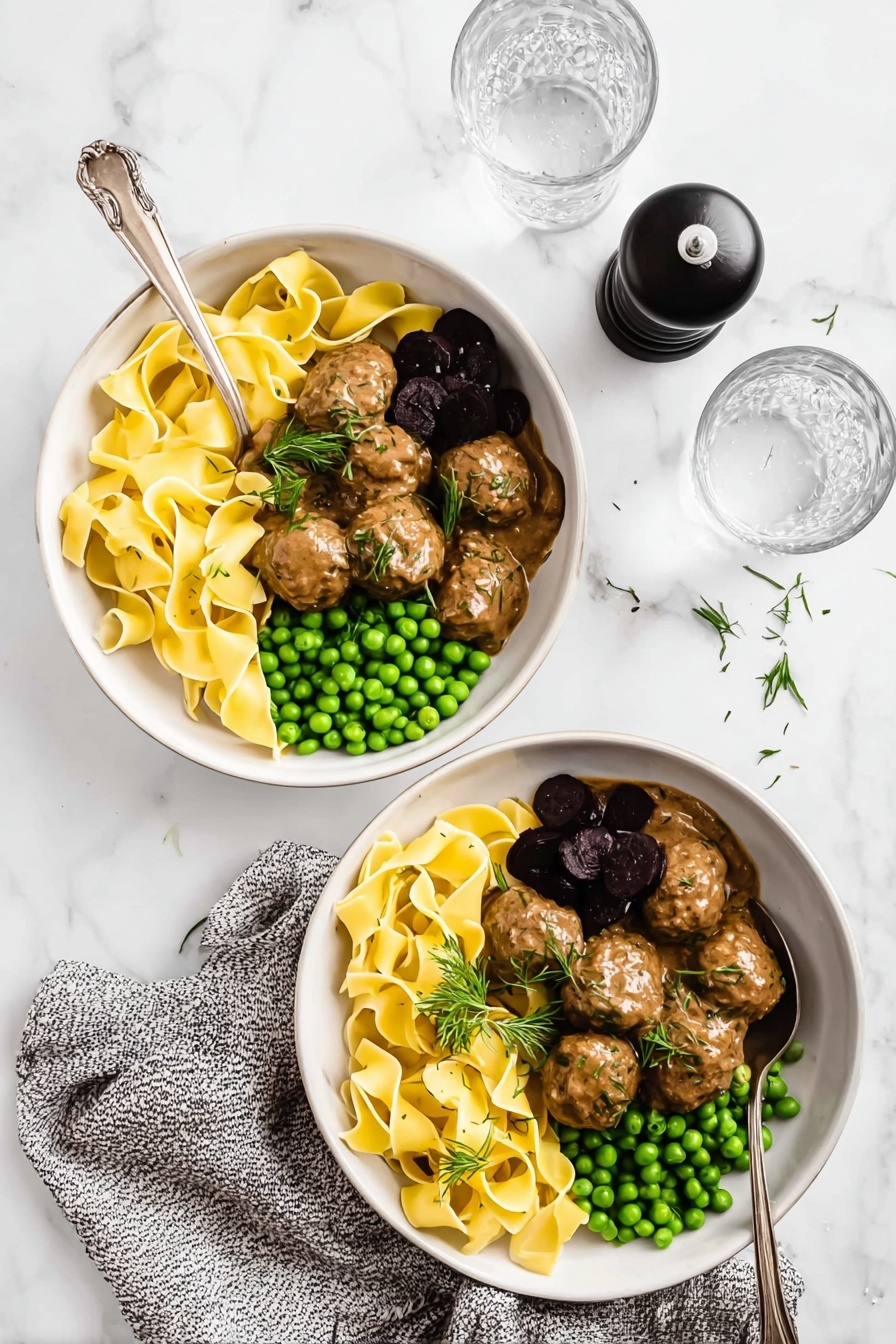Swedish Meatballs with Creamy Gravy, Swedish meatballs, creamy gravy recipe, homemade Swedish meatballs, comfort food recipes - Two white bowls placed on a white marbled surface hold a meal of three layers each. The first layer in each bowl is wide, flat yellow pasta ribbons arranged loosely in a pile on one side with a light sprinkle of herbs. The second layer beside the pasta is a small heap of bright green peas. The third layer, next to the peas, consists of brown meatballs covered in a smooth, creamy brown sauce, garnished with fresh green herbs and one or two dark purple pickled elements. Each bowl has a silver spoon resting inside. A black pepper grinder, a speckled gray cloth, and two clear glasses of water are also arranged on the white marbled surface. Photo taken with an iphone --ar 2:3 --v 7