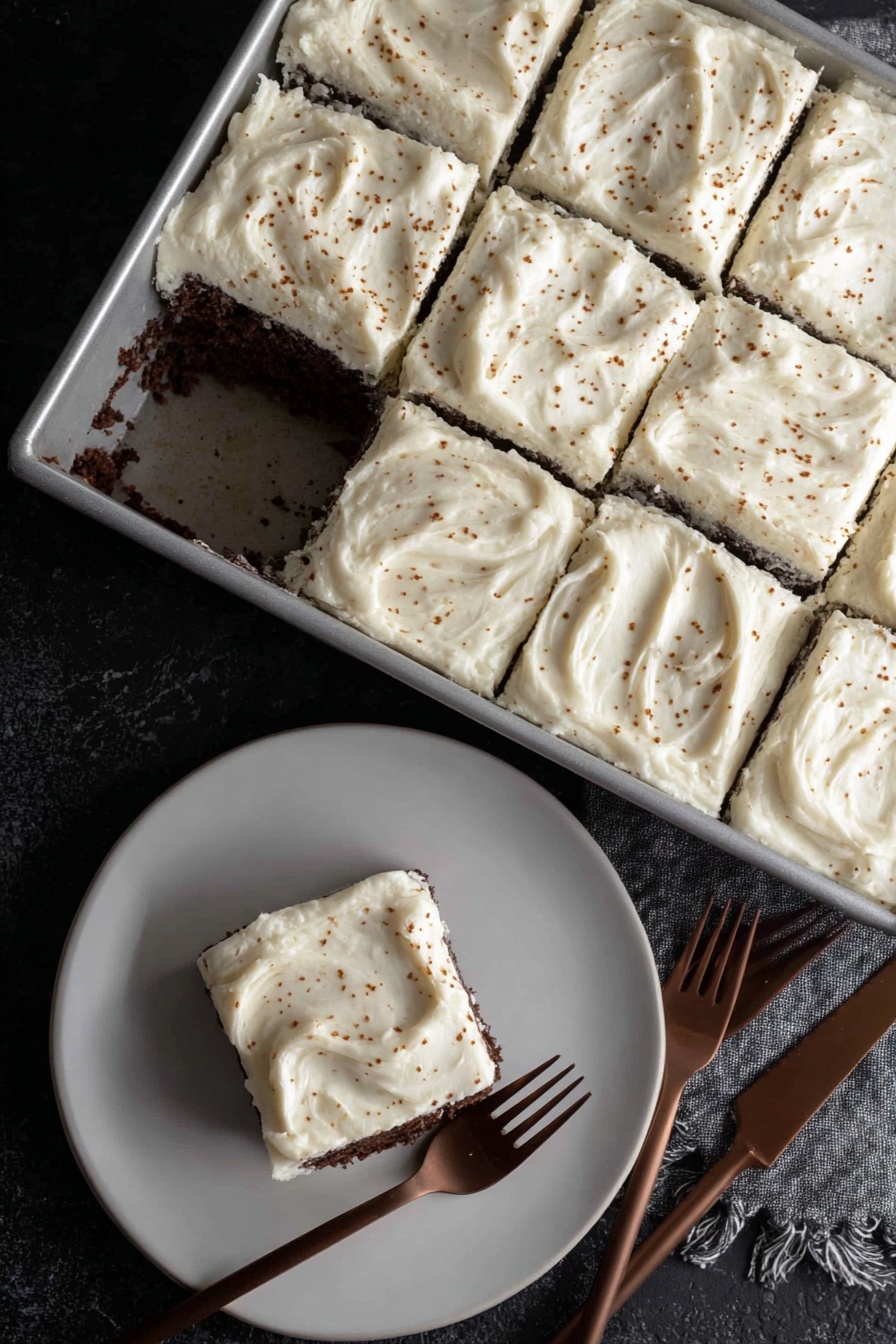 Dark Chocolate Espresso Cake without recipe, decadent chocolate cake, espresso flavored dessert, brown butter frosting recipe, moist chocolate cake - A rectangular metal pan holds a cake cut into nine square pieces, with one piece missing near the center showing a dark, moist chocolate layer under a thick, creamy white frosting. Each frosting layer is spread thick and smooth with slight swirling patterns and small brown specks sprinkled over the top. On a white plate below, one square piece of the cake sits with the same thick white frosting on top and dark chocolate cake layer visible on the sides. Two brown forks lie near the plate on a black textured surface. photo taken with an iphone --ar 2:3 --v 7