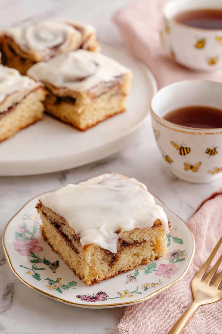 Cinnamon Roll Cake, Easy Cinnamon Roll Cake, No-Fail Cinnamon Roll Cake, Cinnamon Swirl Cake, Breakfast Cinnamon Cake - The image shows three square pieces of cinnamon roll cake with a light brown base and a visible swirl of darker cinnamon filling inside. Each piece is topped with a thick, creamy white icing that spreads unevenly on top. The pieces sit on white plates with delicate gold edges and small floral designs. A white teacup with a gold line on the rim and small floral pattern holds dark brown tea, positioned beside one of the plates. A gold fork rests on a soft pink napkin near the front plate. The background is a white marbled surface, and a tray with more pieces is visible in the back. Photo taken with an iphone --ar 2:3 --v 7