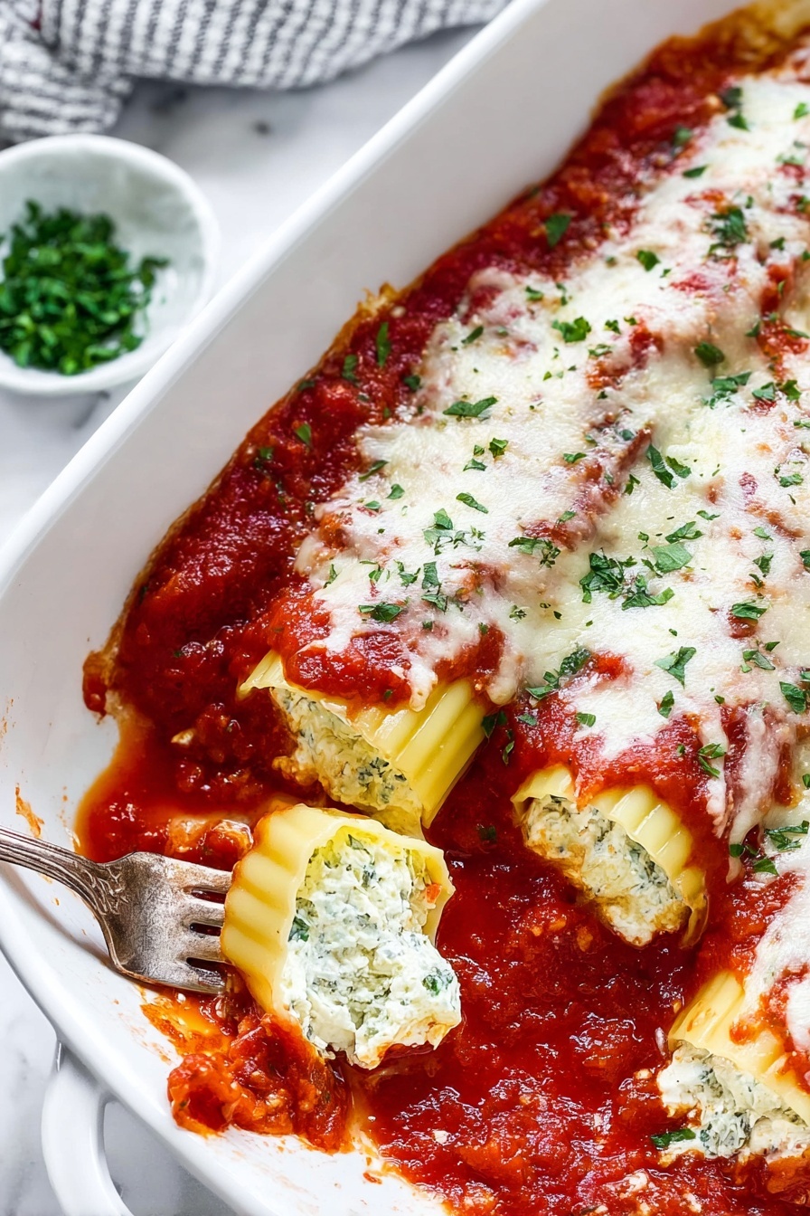 Cheese Manicotti with Flavorful Tomato Sauce, cheesy pasta bake, Italian manicotti recipe, homemade tomato sauce, baked cheese manicotti - The image shows a white rectangular baking dish filled with two rows of stuffed pasta shells, each covered with a layer of chunky red tomato sauce, melted white cheese, and sprinkled with fresh green herbs. The pasta shells are a pale yellow color with ridged edges visible beneath the sauce and cheese. Around the dish, on a white marbled surface, there are small bowls with green herbs and grated cheese, and some fresh red tomatoes on the vine. The overall look is warm and freshly baked with slight sauce splatters on the edge of the dish, photo taken with an iphone --ar 2:3 --v 7
