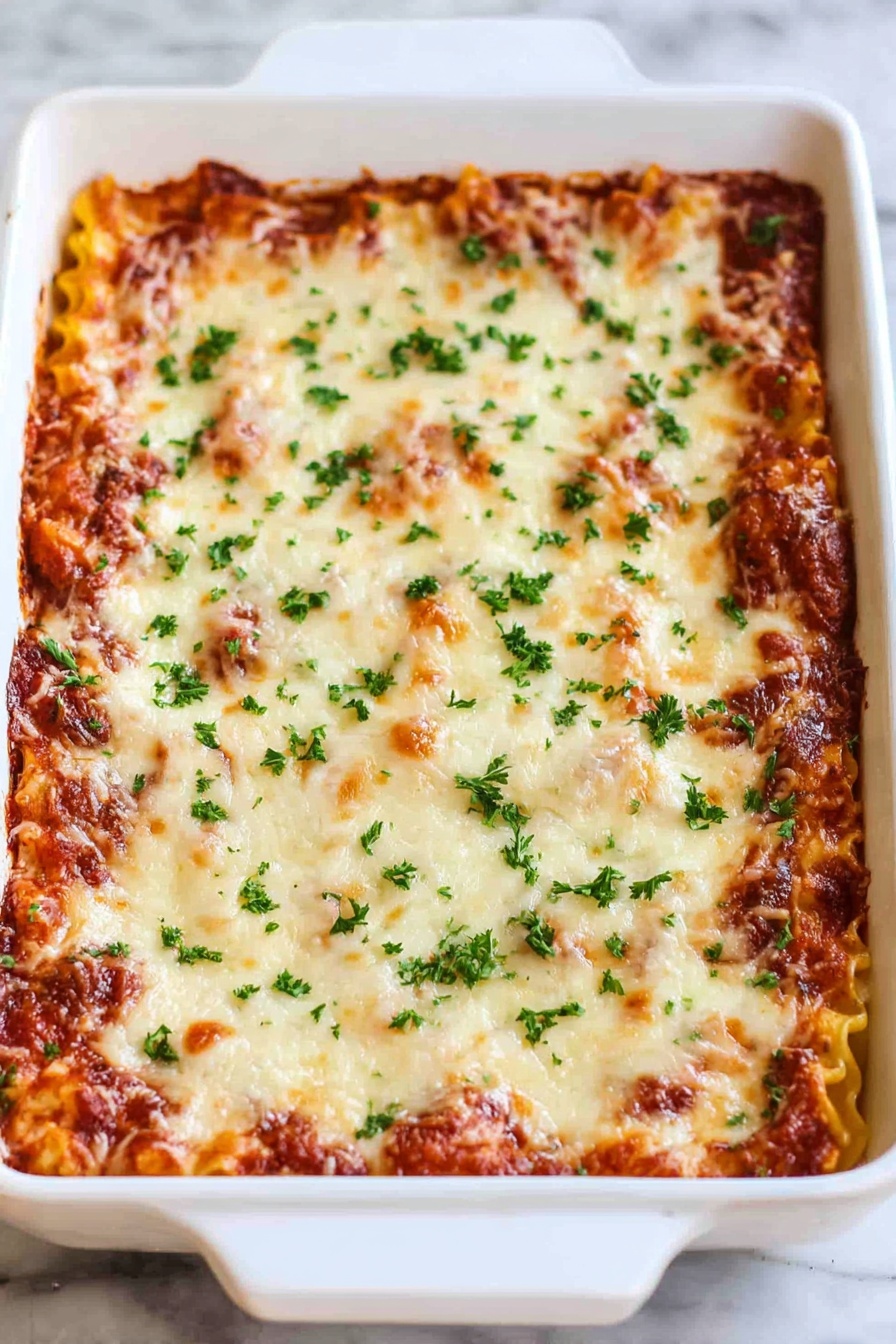 Cheesy Beef Lasagna Roll Ups, cheesy beef lasagna, lasagna roll ups, cheesy pasta casserole, family dinner ideas - A white rectangular baking dish filled with a layered lasagna. The top layer is melted cheese with golden brown spots and sprinkled with small green parsley pieces. The layer underneath shows hints of a rich red tomato sauce and pasta edges peeking through. The dish is placed on a white marbled surface. photo taken with an iphone --ar 2:3 --v 7