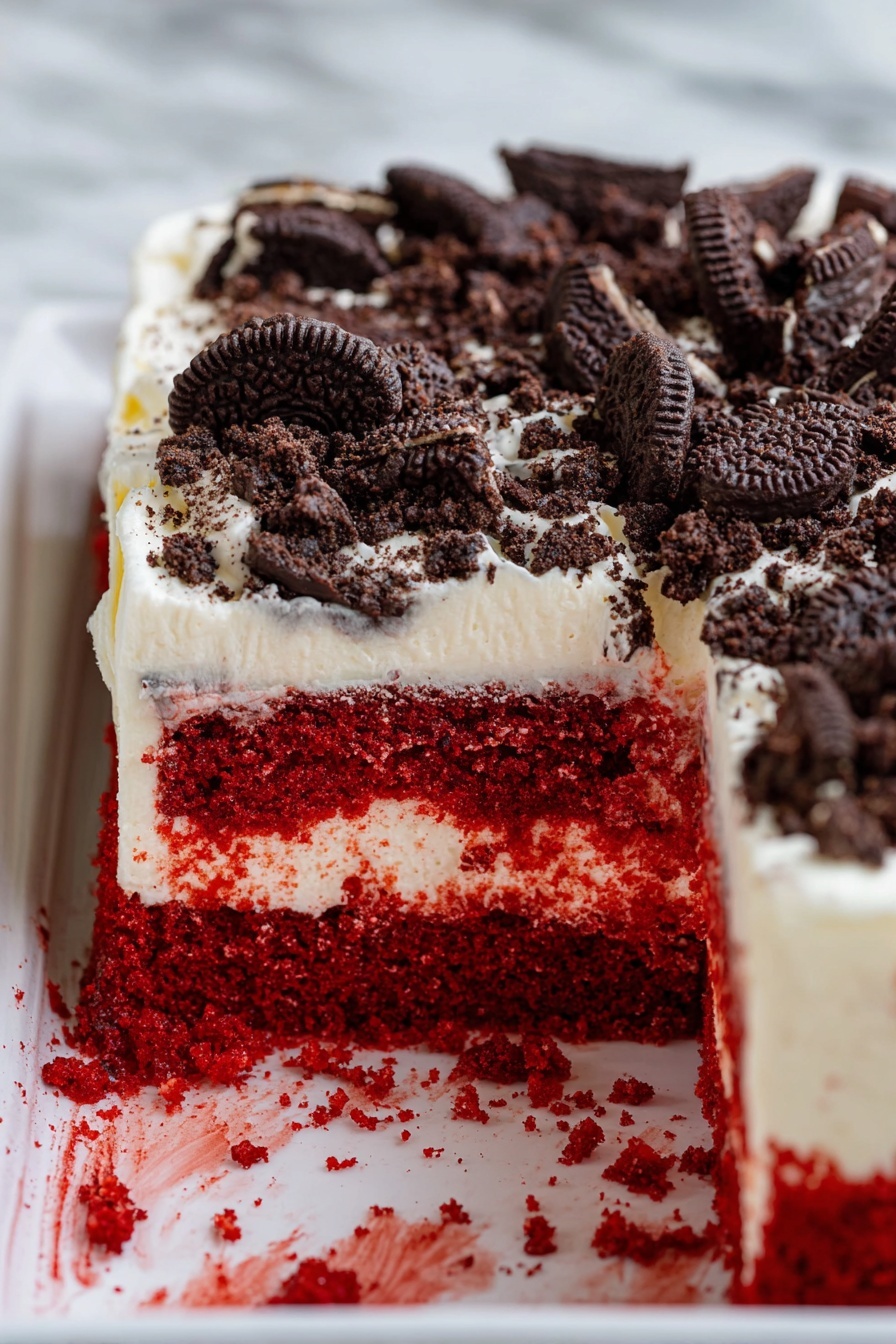Red Velvet Poke Cake with Cheesecake Pudding, red velvet poke cake, cheesecake pudding dessert, easy red velvet cake, decadent poke cake - The image shows a close-up of a rectangular red velvet cake with a thick layer of creamy white frosting on top. On top of the frosting, there are many crushed chocolate cookies spread evenly. The cake is inside a white tray placed on a white marbled surface. A portion of the cake is taken out, revealing two clear layers: the bottom layer is bright red and moist, while the top layer is the creamy white frosting with some red parts from the cake blending in. Some red crumbs and frosting bits are on the tray near the cut-out section. Photo taken with an iphone --ar 2:3 --v 7