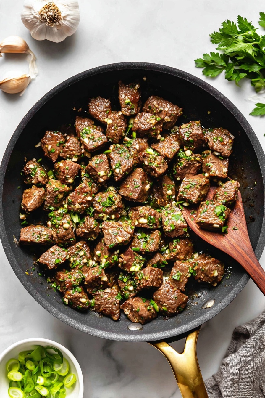Garlic Butter Steak Bites, garlic butter steak, quick steak dinner, flavorful steak recipe, easy steak bites - The image shows a black pan filled with many small brown meat cubes cooked with small bits of white garlic and green parsley sprinkled on top, giving a fresh look. The pan has a golden handle at the bottom right, and a wooden spoon rests inside the pan on the right side, slightly lifting some meat. Around the pan, on a white marbled surface, there are two garlic cloves and a few green parsley leaves at the top left and a small white bowl filled with sliced green onions at the bottom left, adding color contrast. The overall look is warm and savory, with the textures of the meat and herbs clearly visible. photo taken with an iphone --ar 2:3 --v 7