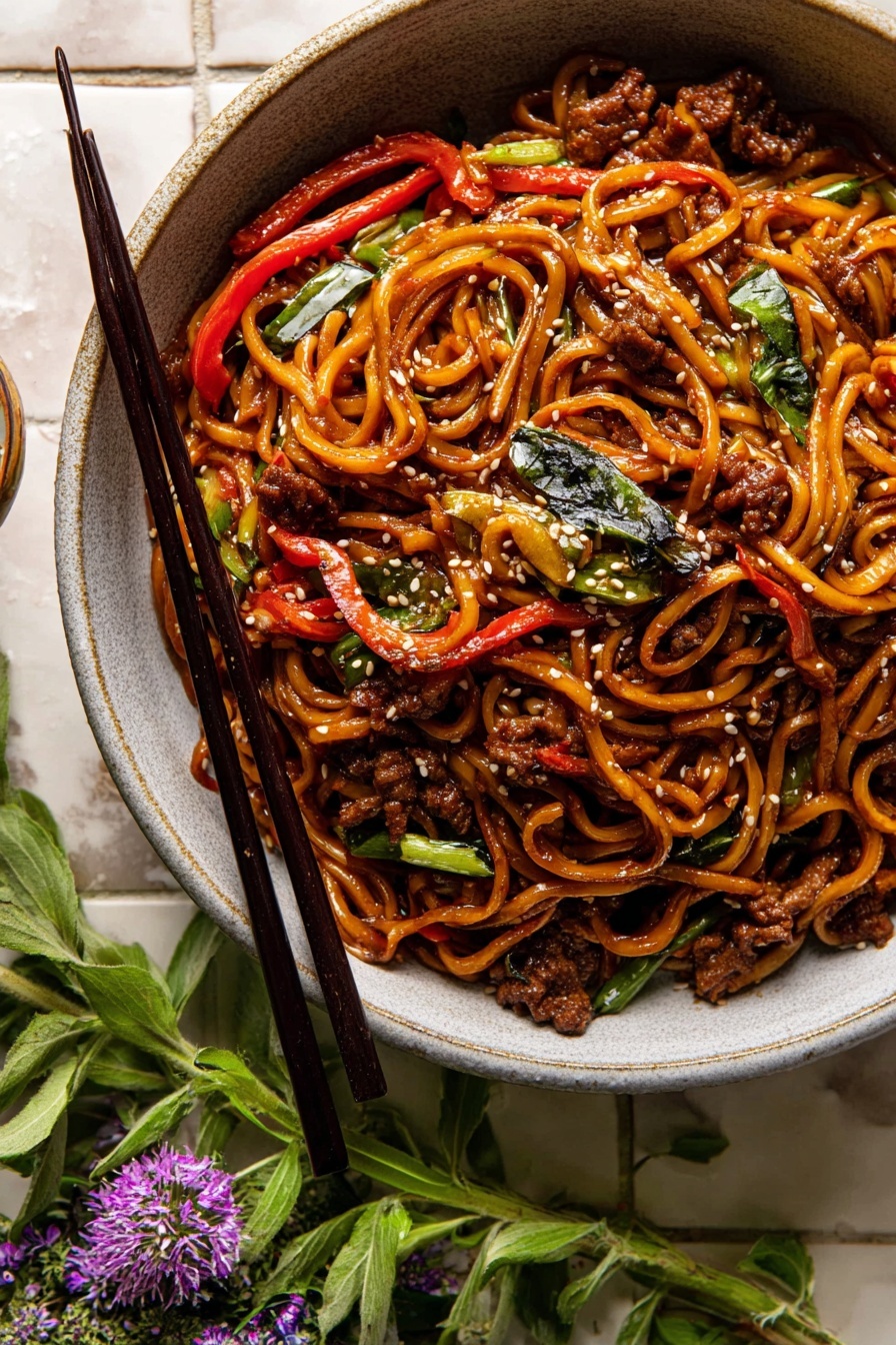 Korean Beef Sesame Noodles, Korean Beef Noodles, Sesame Noodles with Beef, Asian-Inspired Noodle Recipe, Quick Korean Beef Noodles - A bowl filled with glossy, dark brown noodles mixed with small pieces of cooked brown meat, thin red pepper strips, and scattered green leafy herbs. White sesame seeds are sprinkled over, adding texture. The bowl itself is light gray with a slightly rough texture and is placed on white marbled square tiles. Black chopsticks rest on the left side of the bowl, and fresh green herbs with small purple flowers lay near the chopsticks. The photo has warm lighting that highlights the glossy and soft textures of the noodles and ingredients. photo taken with an iphone --ar 2:3 --v 7